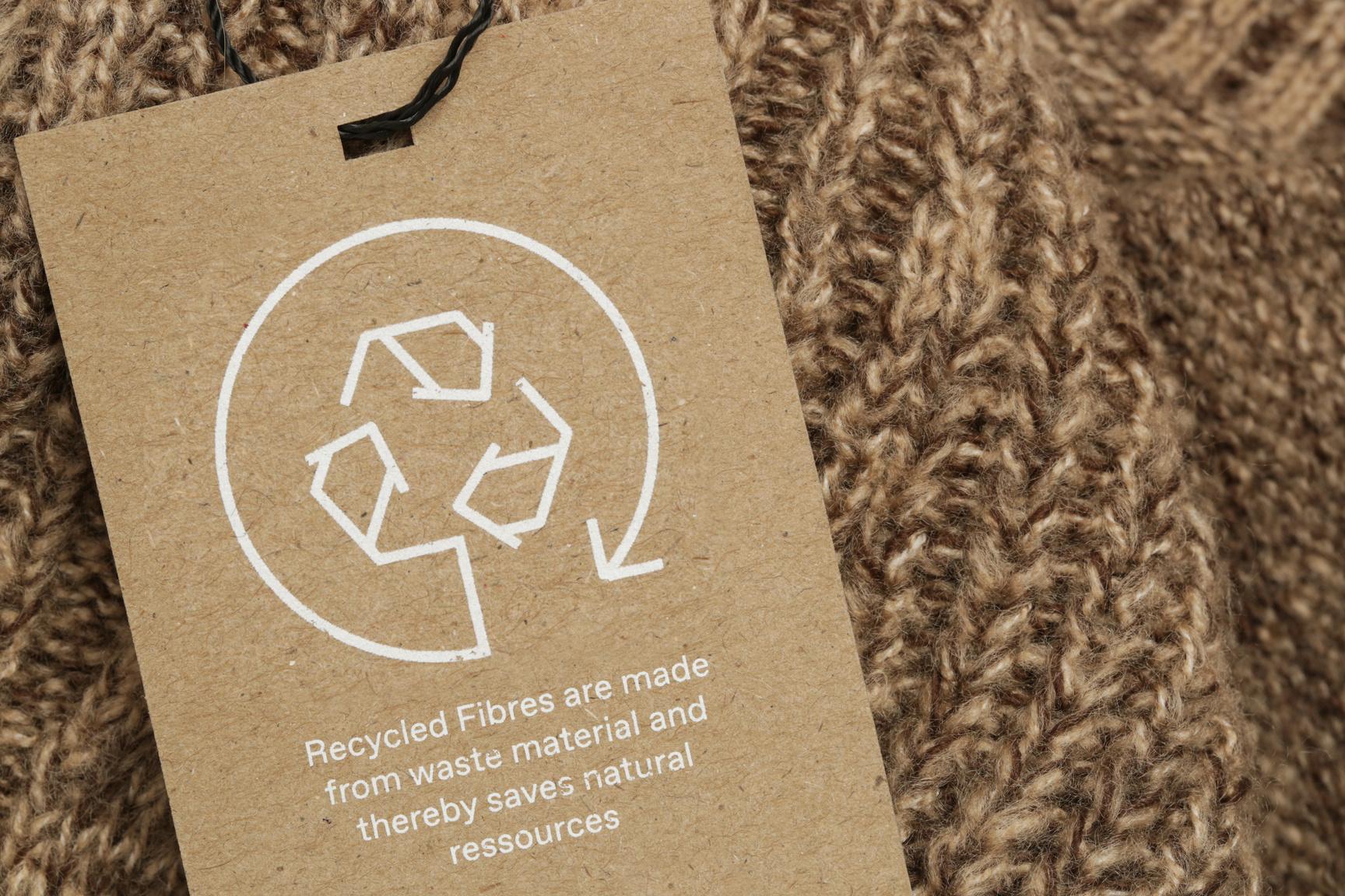 Close up of clothing tag with recycle icon. Recycling products concept. Zero waste, suistainale production, environment care and reuse concept.